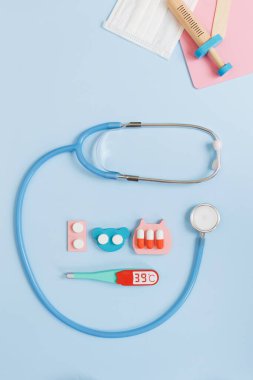 Mavi arka planda tıbbi düz konsept. Şirin ahşap ilaç oyuncakları, doktorculuk, fotokopi alanı ile pediatrik konsept