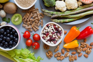 Dengeli beslenme geçmişi. Taze sebzeler, meyveler, tahıllar, tohumlar ve fındıklar mavi arka planda.
