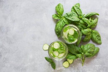 Taze yeşil sebze kokteyli. Fesleğenli moktail ve salatalık. Gri arka planda yeşil taze içecek.