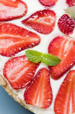 Taze çilekli ve naneli cheesecake. Beyaz kremalı, kırmızı böğürtlenli ve yeşil nane yapraklı lezzetli pasta.