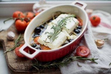 Fırında makarna peyniri, domates, zeytin, sarımsak, yağ, bal ve biberiye.