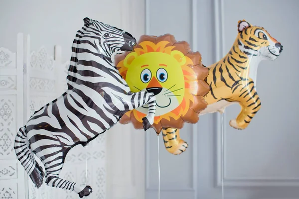 Jungle party animal balloons decorations. Child's birthday party with colorful balloons near white wall