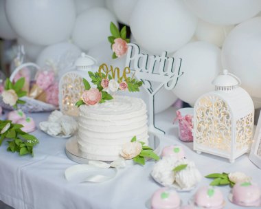 Beyaz kremalı ilk doğum günü pastası, kağıt çiçekli altın pasta süsü. Küçük kız için beyaz doğum günü partisi