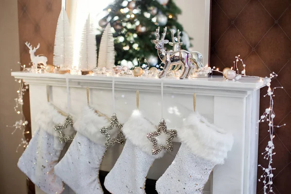 白色的圣诞袜和银星 还有挂在壁炉上的铃铛袜子里的圣诞礼物 — 图库照片