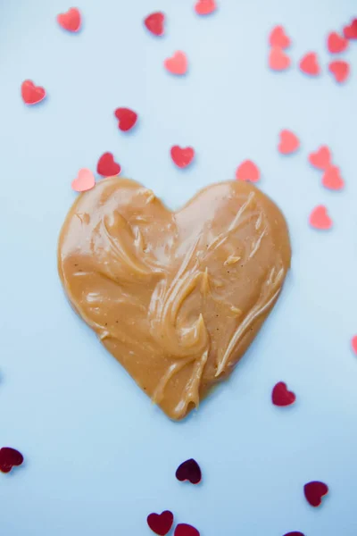 Heart Shaped Caramel Sauce Candy Blue Background Red Hearts Confetti — Stock Photo, Image