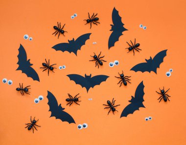 Turuncu arka planda siyah süslemeli Cadılar Bayramı deseni. Siyah kağıt yarasa, karıncalar ve gözler, Cadılar Bayramı parti süslemeleri