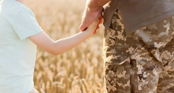 Asker ve çocuk gün batımında buğday tarlasında el ele tutuşuyorlar. Ukrayna 'nın bağımsızlık günü kavramı. Ukrayna 'daki savaşı durdurun. Ukrayna 'yı Kaydet