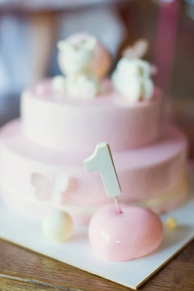 Pink cake with mirror glaze and white chocolate unicorn . Cake on a white cake stand. First birthday party concept