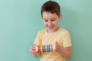 Caucasian preschool boy with arithmetic math learning toy on a light green background with copy space