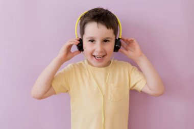 Caucasian boy in headphones on a pink background with copy space