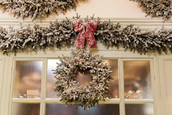 Decorated Christmas garland with red bow and round wreath on a showcase of bakery