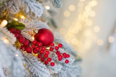 Kırmızı top süslemeli Noel ağacı, kırmızı böğürtlen dalı ve arka planda hoş bir ışık çelengi. Kopya alanı olan Noel afişi