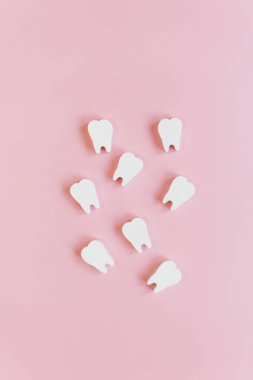 Pembe arka planda beyaz dişler ve fotokopi alanı. Diş hekimliği, dişçi kliniği konsepti.