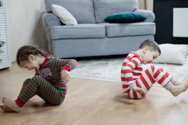 Anaokulu çocuğu ve kız Noel pijamalarıyla yerde silikon giyiyorlar.