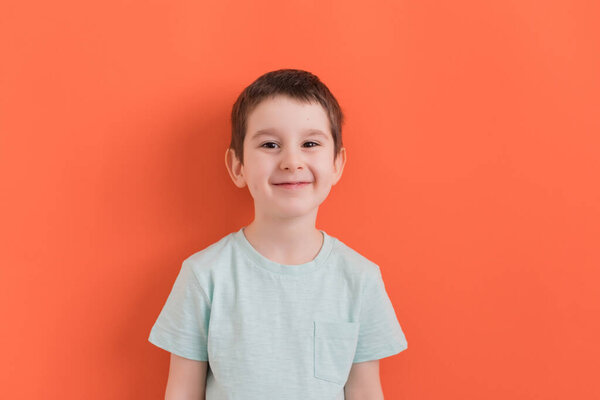 Happy and smiling preschool boy on an orange background with copy space