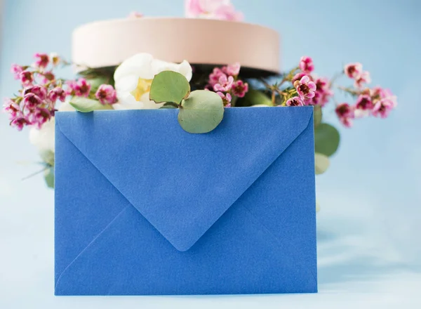 Blue envelope and pink gift box with bouquet on a blue background