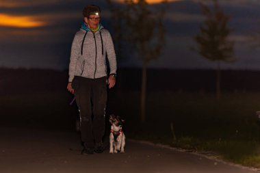 Kadın, sonbaharda elinde fenerle bir köpekle gezer. Jack Russell Terrier.