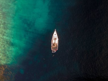 Hırvatistan 'ın Vis Adası' ndaki renkli resiflerdeki yelkenli teknesinin insansız hava aracı görüntüsü