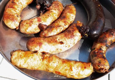 Tipik geleneksel Arjantin yemekleri. Izgara sakatat, domuz sosisi ve siyah puding gümüş paslanmaz çelikte ve açık havada güneş altında.  