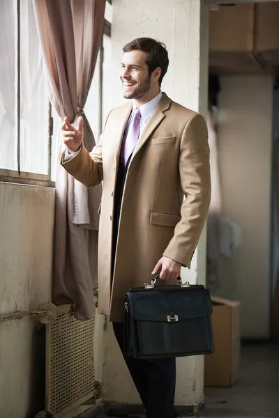 Uomo d'affari sorridente che guarda fuori dalla finestra — Foto Stock