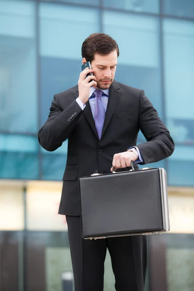 Uomo d'affari che parla al telefono e guarda orologio — Foto Stock