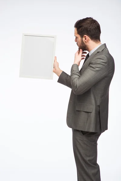 Eleganta mannen tittar på en inramad styrelse — Stockfoto