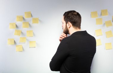 bir duvar ile postits yanında duran adam