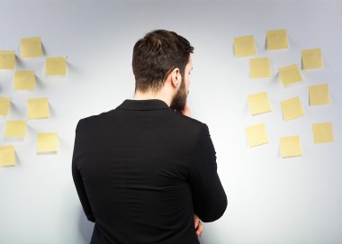 bir duvar ile postits yanında duran adam