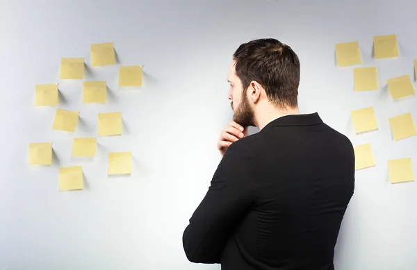 Man står intill en vägg med postits — Stockfoto