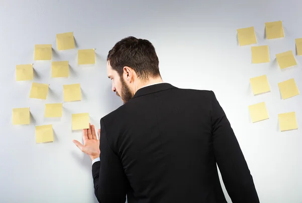 Man står intill en vägg med postits — Stockfoto