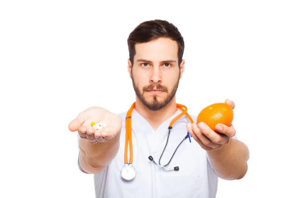 Doctor masculino mostrando naranja y pastillas —  Fotos de Stock