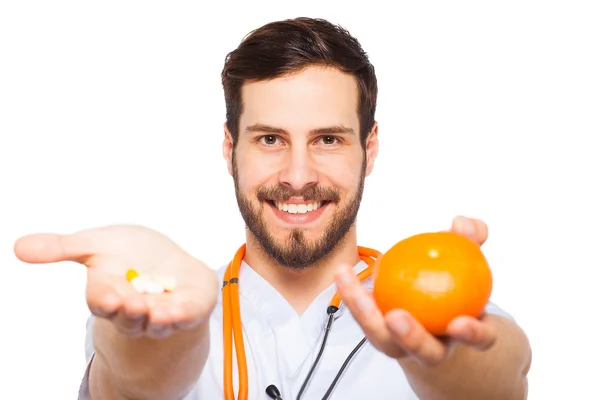 Médico masculino mostrando laranja e pílulas — Fotografia de Stock