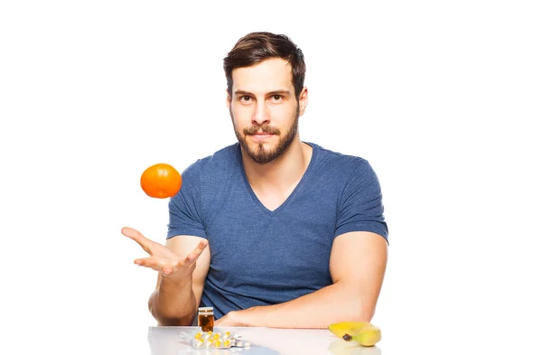 Hombre que tiene en frente píldoras y frutas, la elección entre ellos — Foto de Stock