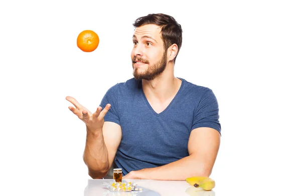 Человек, имеющий в передней таблетки и фрукты, выбирая между ними — стоковое фото