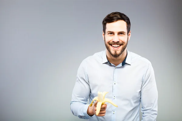 Retrato de um jovem sério inteligente comendo banana — Fotografia de Stock