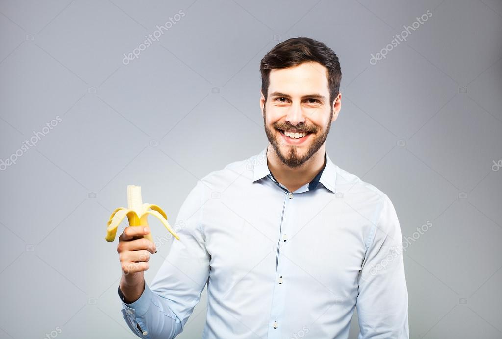 Portrait of a smart serious young man eating banana