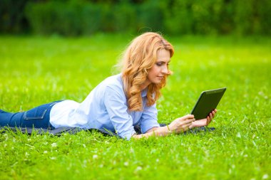 sarışın kadın ile bir tablet ellerinde yeşil çim yalan