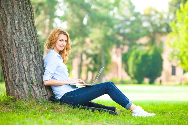 Schöne Frau sitzt mit Laptop im Park — Stockfoto