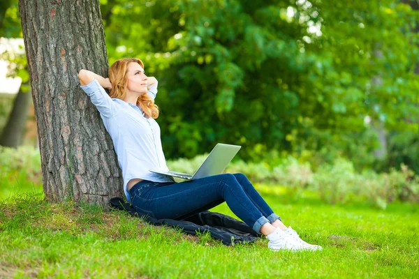 Schöne Frau sitzt mit Laptop im Park — Stockfoto