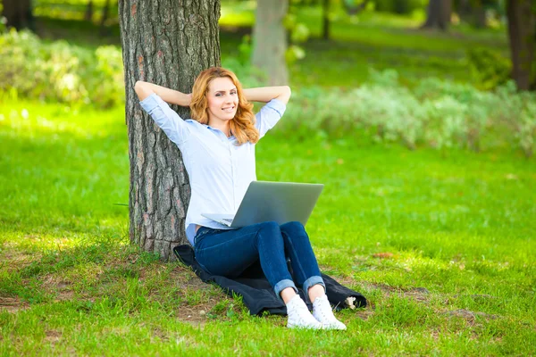 Hermosa mujer sentada en el parque con portátil — Foto de Stock