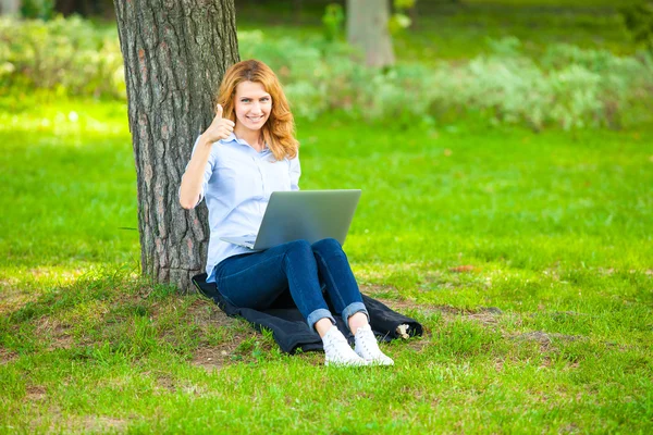 Schöne Frau sitzt mit Laptop im Park — Stockfoto