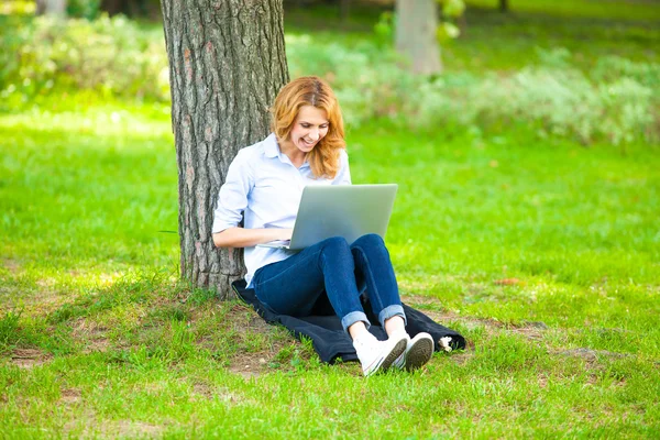 Femeie frumoasă care stă în parc cu laptop — Fotografie, imagine de stoc