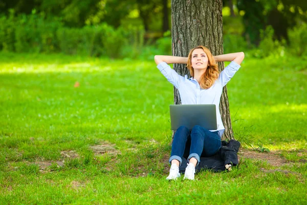 Schöne Frau sitzt mit Laptop im Park — Stockfoto