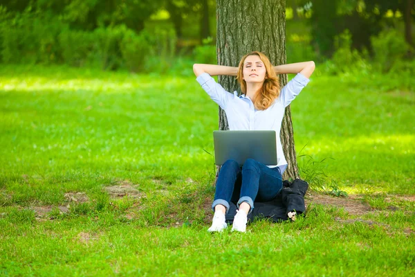 Beautiful woman sitting in park with laptop — Stock Photo, Image