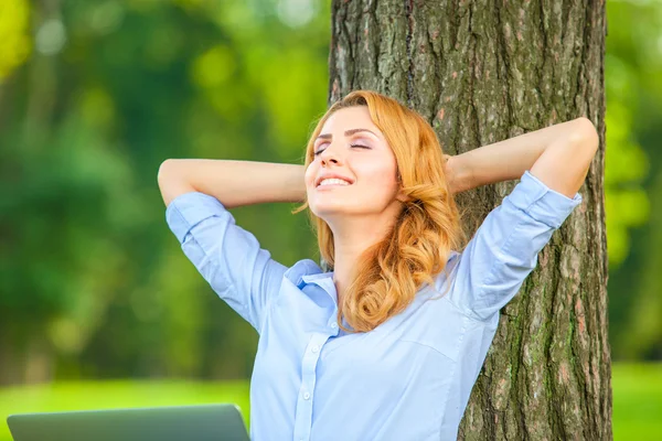 Mooie vrouw zitten in park met laptop — Stockfoto