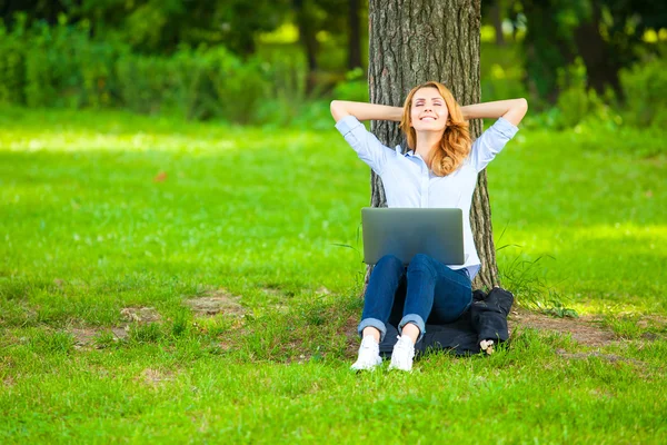 Krásná žena, sedí v parku s notebookem — Stock fotografie
