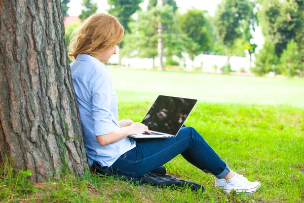 Dizüstü bilgisayar ile parkta oturan güzel kadın — Stok fotoğraf