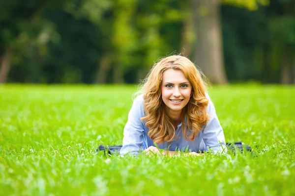 Beautiful lady lying in green grass — Stock Photo, Image