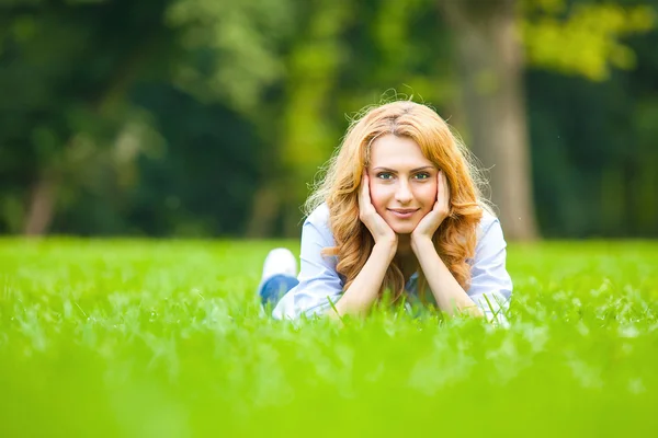 Lächelnde blonde Frau im grünen Gras, die Liebe zeigt — Stockfoto