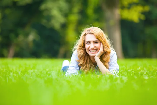 Улыбающаяся блондинка в зеленой траве показывает любовь — стоковое фото